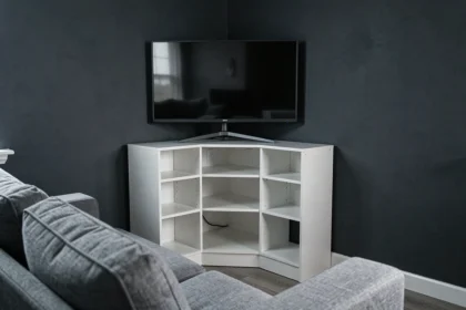 Meuble TV d'angle blanc dans un salon aux murs gris anthracite, apportant une touche lumineuse dans un espace sombre